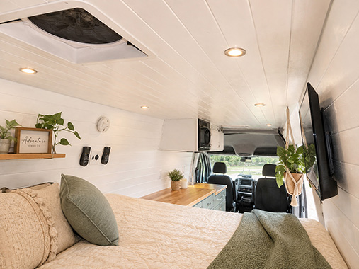Bed of the Billy Goat camper van conversion with a slatted ceiling and marine-grade 12V electrical system.